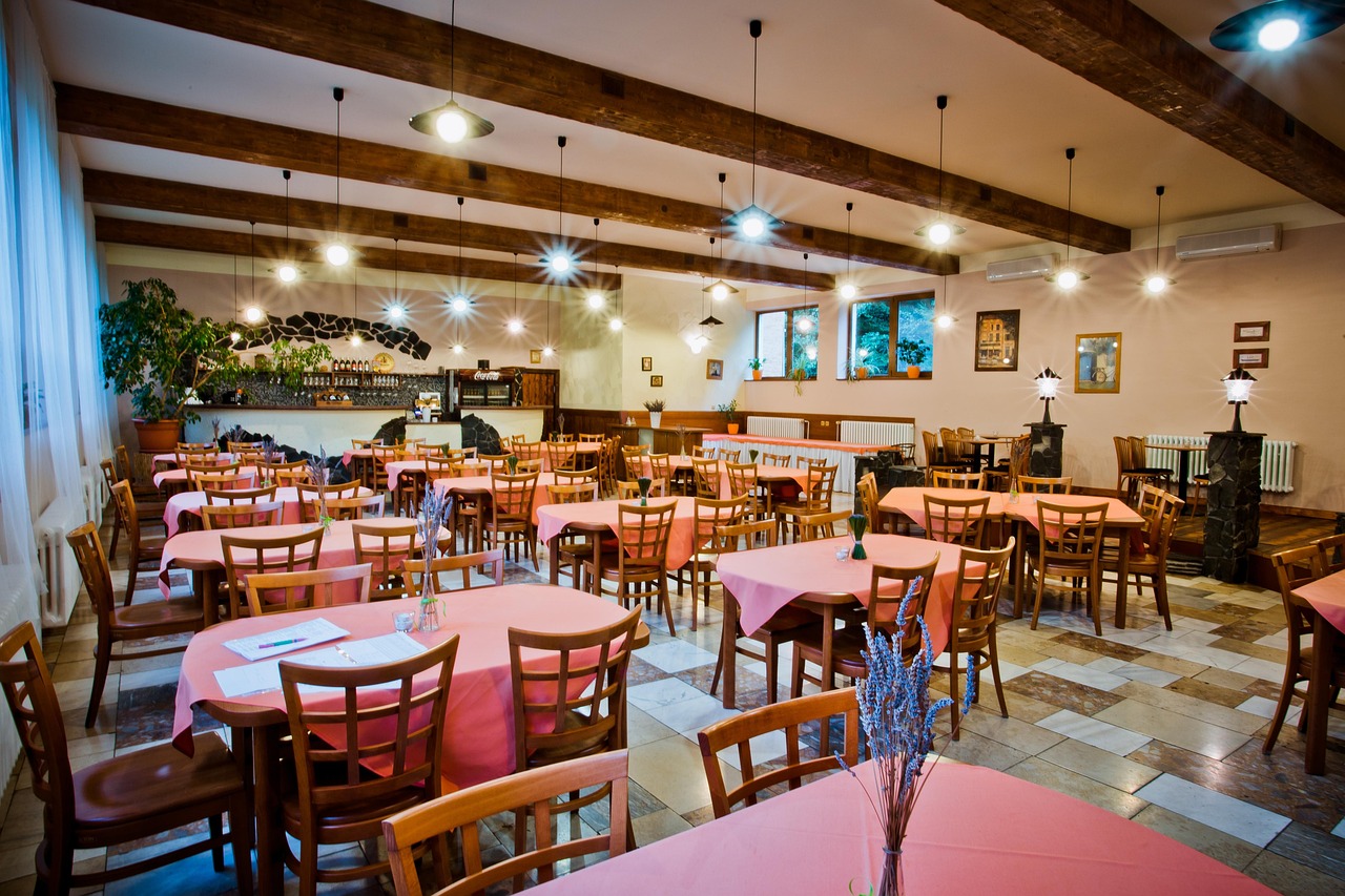 Spacious restaurant dining area with exposed wooden beams, pendant lighting, and comfortable seating for expanded capacity in Fredericksburg, Virginia